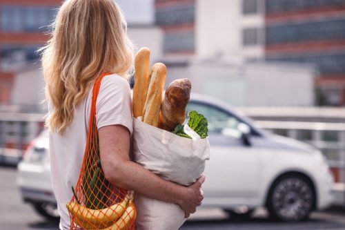 woman carrying groceries on car