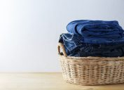 Quần áo và quần jean trong giỏ giặt trên sàn gỗ