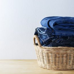 Clothes and jeans in a laundry basket on Wood floor