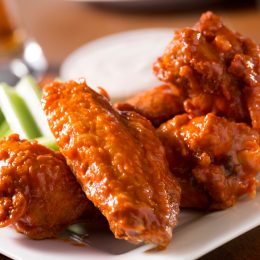 A plate of buffalo style chicken wings with celery and blue cheese with a beer on a bar or restaurant table. Please see my portfolio for other food and drink images.