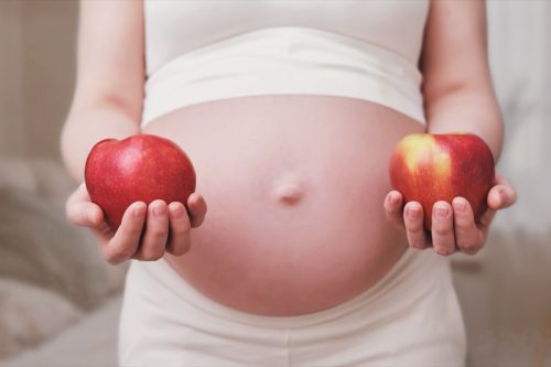 pregnant woman holding two red apples