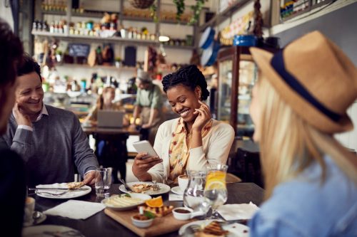 Cận cảnh một nhóm bạn đang thưởng thức đồ ăn tại nhà hàng và sử dụng điện thoại di động