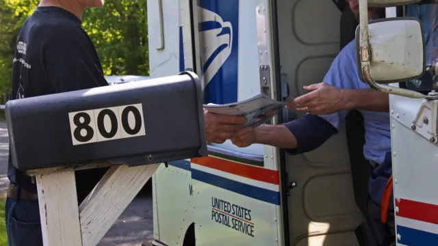 Postal worker hands a man his mail