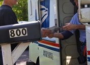 Một nhân viên bưu điện đưa một lá thư cho một người đàn ông
