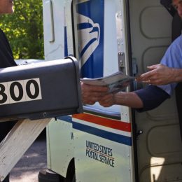 Postal worker hands a man his mail