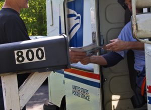 Postal worker hands a man his mail