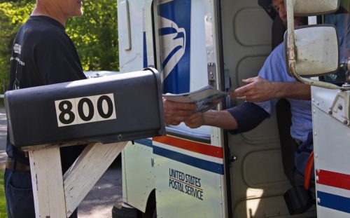 Postal worker hands a man his mail