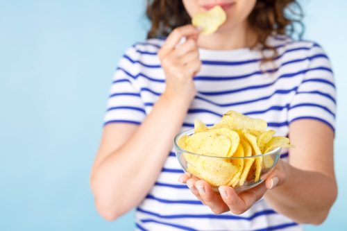 Young woman with chips on blue background