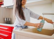 Close up of woman fills up reusable water bottle in the kitchen
