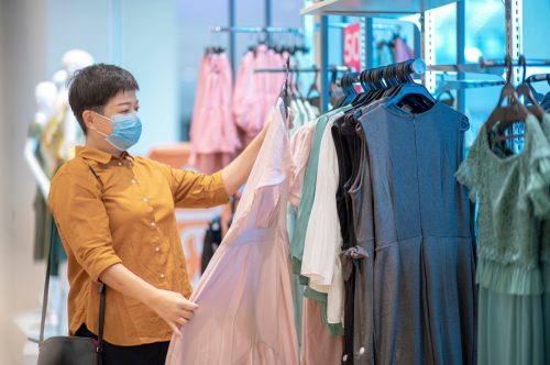 female hand holding dress and looking at clothing store choosing