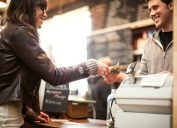 Một người phụ nữ thanh toán hóa đơn cho nhân viên thu ngân trong quán cà phê