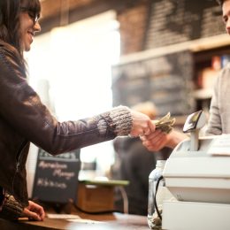 A woman paying a cashier with bills at a coffee shop