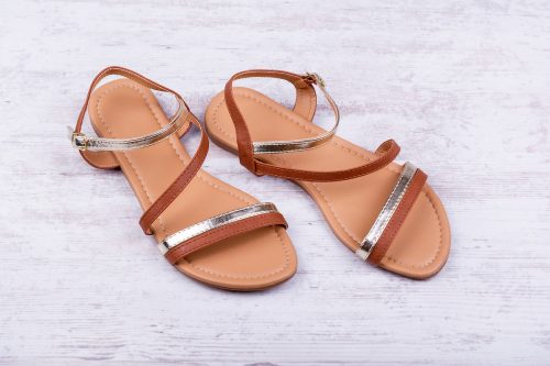 Pair of women's sandals on a white wooden background.
