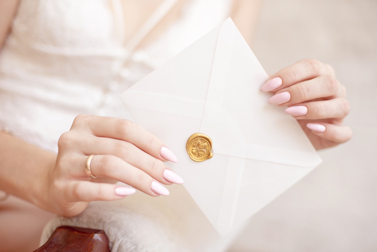 close-up woman with slim body holding invitation envelope card in hands, rear veaw.