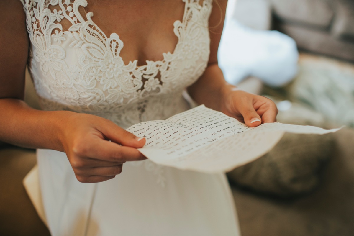 Bride reading handwritten letter from groom on wedding day