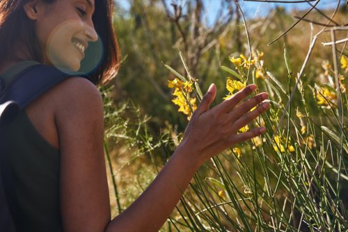 Joyful Young Woman Touching Flowers
