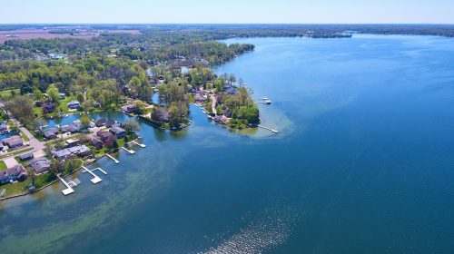 Lake houses on distant shore aerial asset water property green algae in water piers and docks
