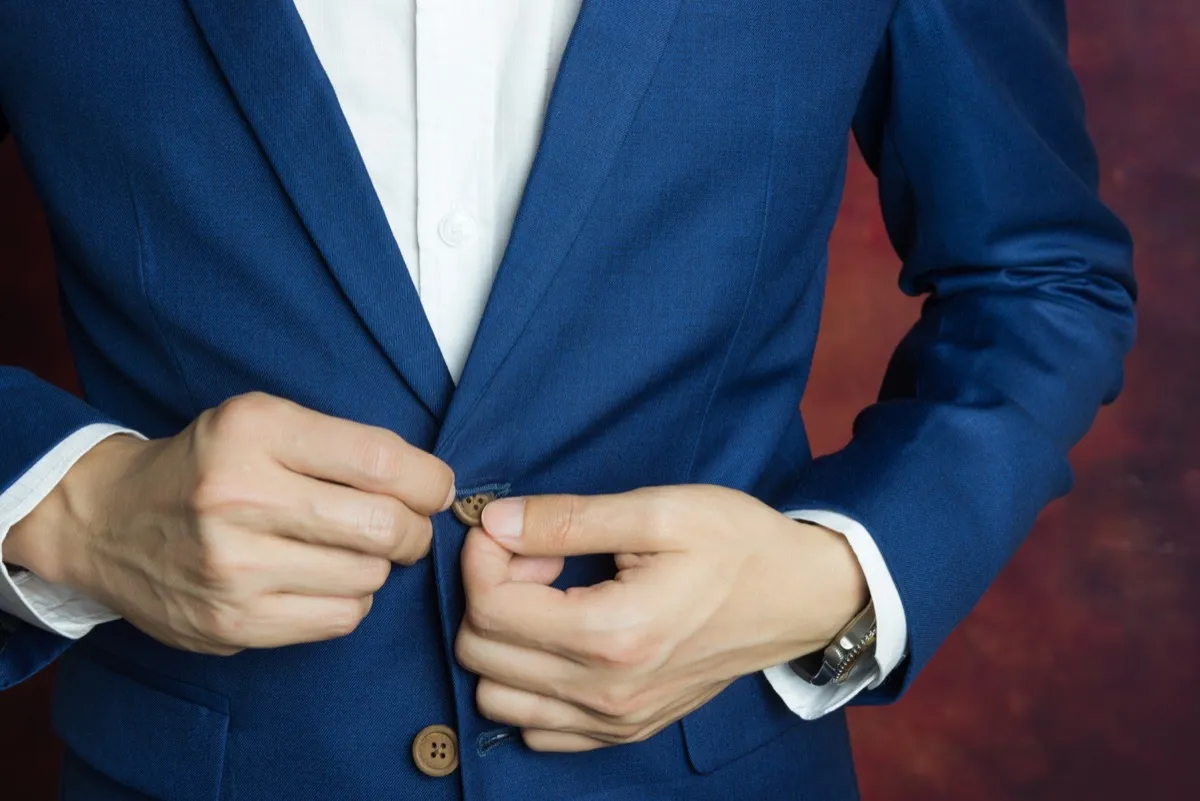 Man in navy blue suit two buttons, doing button