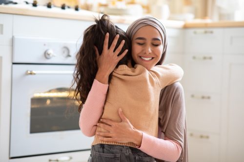little girl and her mother hugging in the kitchen