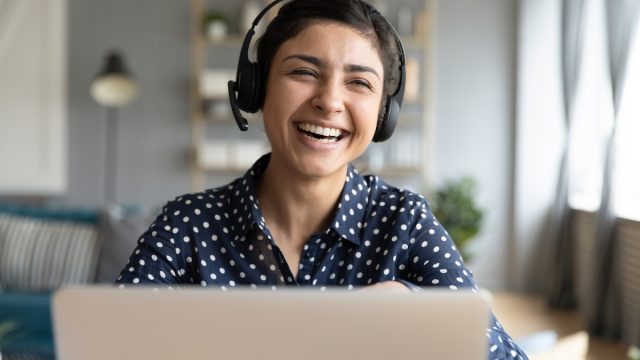 Cheerful woman wear headset laugh using laptop video stream conference call