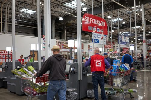 Self checkout lanes in a Costco Wholesale store in Tigard, a southwestern suburb within the Portland metro area. Staff uniform is seen advertising Costco App.