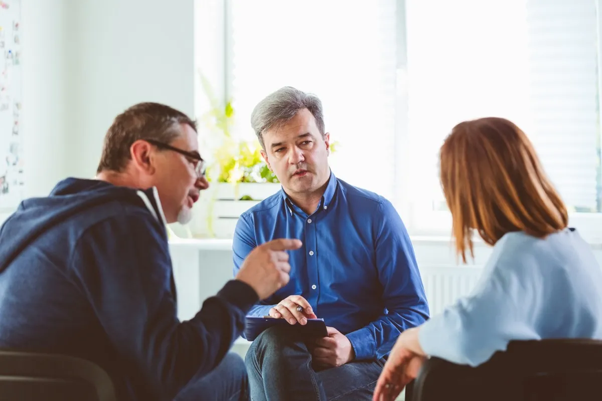 Couple meeting with a therapist; the man is pointing his finger at his wife