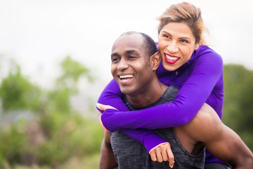 Couple in workout clothes embracing outside, she is wearing a purple top