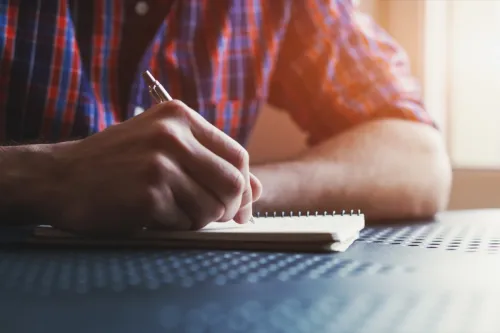 man writing love letters for girlfriend in notebook