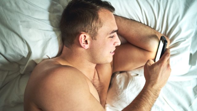 man sexting his girlfriend from bed using dirty emojis