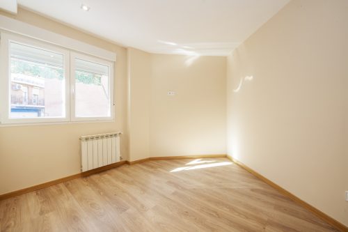 Empty living room with oak laminate flooring, cream painted walls