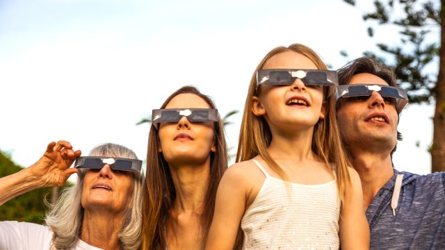 Four people using solar safety glasses to look at the sun