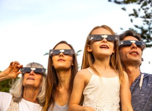 Four people using solar safety glasses to look at the sun