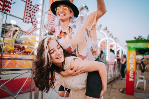 A woman piggybacking on another woman's back at a carnival