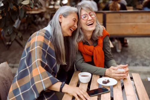 hai người phụ nữ lớn tuổi cười bên tách cà phê