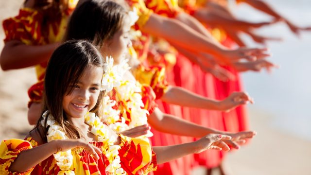 Hula girls with Hawaiian names on the beach with Hands raised