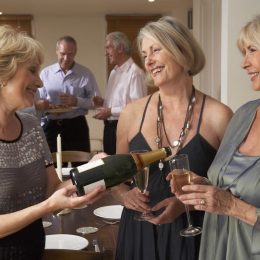 Woman Serving Champagne To Her Guests At A Dinner Party