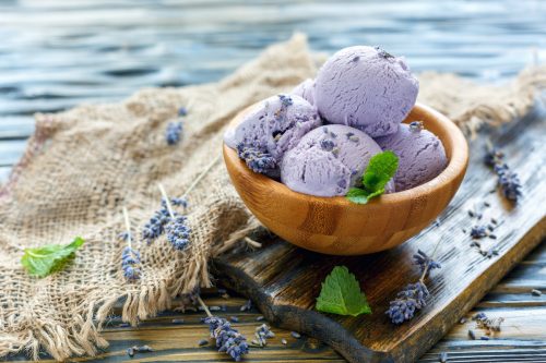 Lavender ice cream scoops in a wooden bowl on an old table with burlap