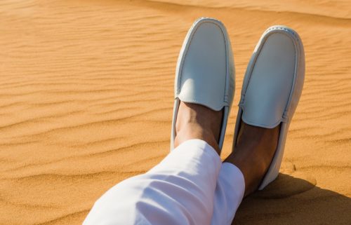 Crossed legged man wearing sandals in a desert 