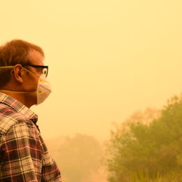 A man wearing a mask while standing in wildfire smoke