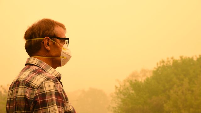A man wearing a mask while standing in wildfire smoke