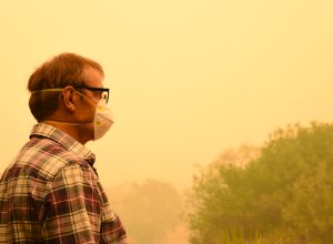 A man wearing a mask while standing in wildfire smoke