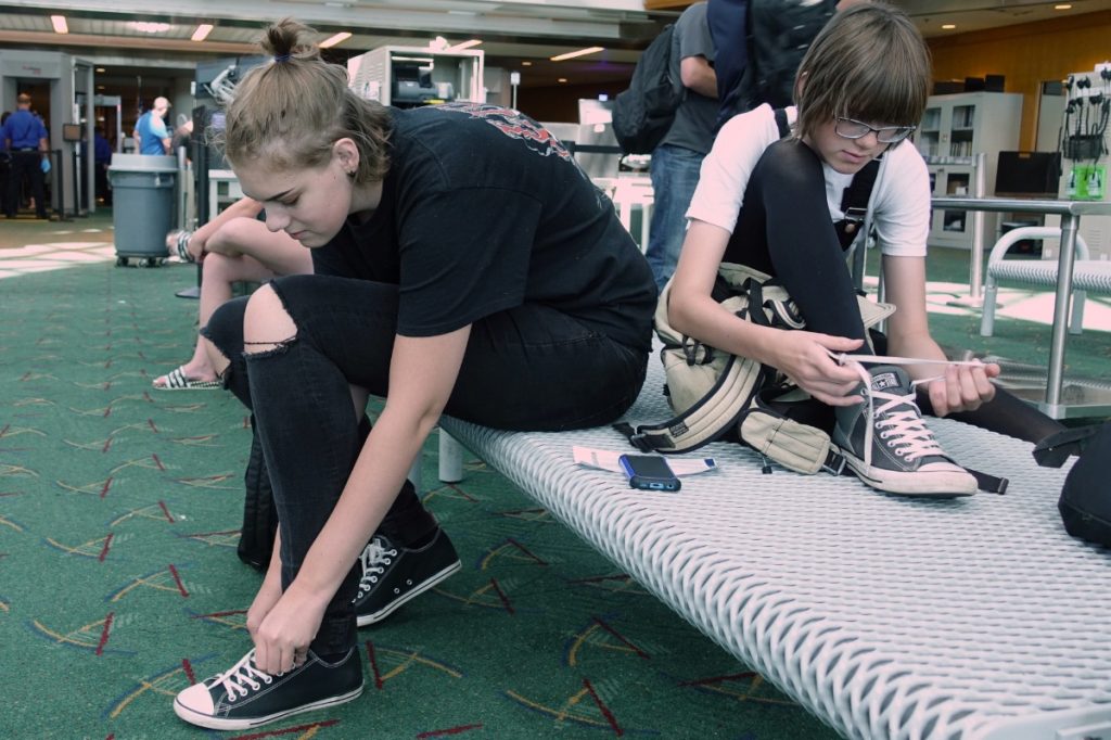 A pair of passengers tying their shoes after going through airport security.