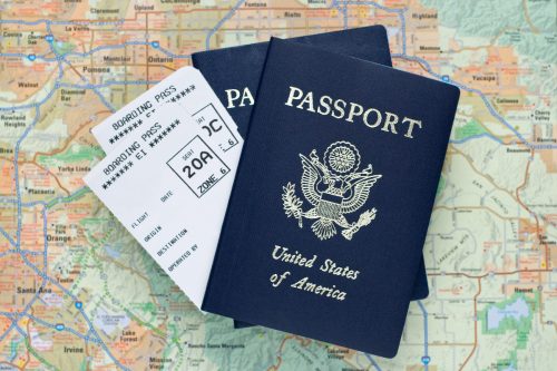 Two U.S. passports and airplane tickets with a map in the background.