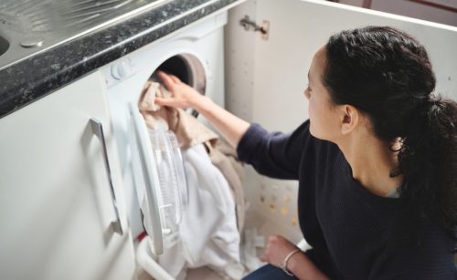 Hình ảnh một người phụ nữ đang giặt quần áo ở nhà.