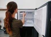 Rear view of a young brunette woman putting something in the freezer