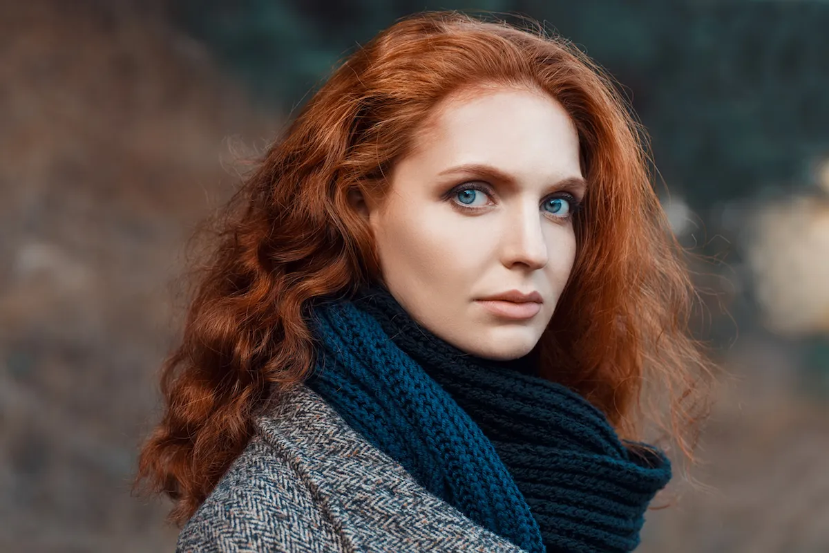 Chân dung cận cảnh người phụ nữ xinh đẹp với mái tóc đỏ và đôi mắt xanh đang tạo dáng ngoài trời