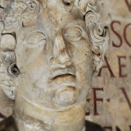 Close up of classical Roman statue against Latin inscription