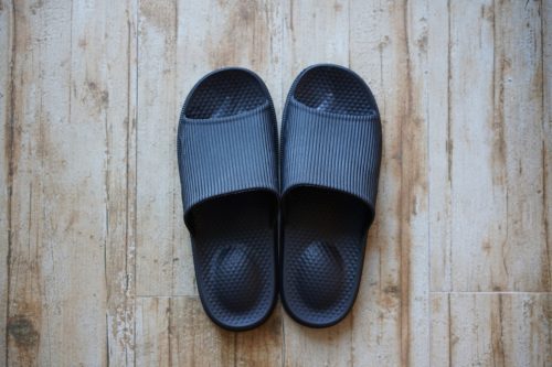 black slide sandals on wooden floor