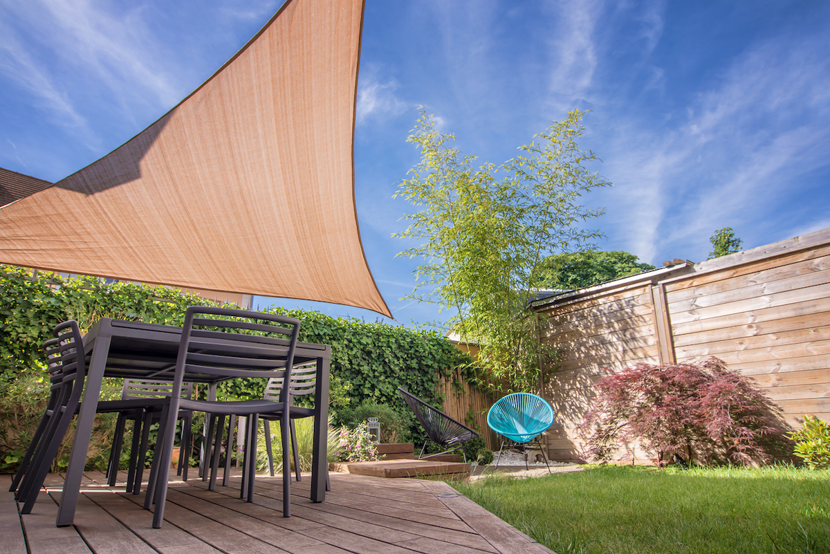 A modern backyard with a sun shade sail over the table