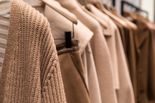 Brown and tan sweaters and coats hanging in closet